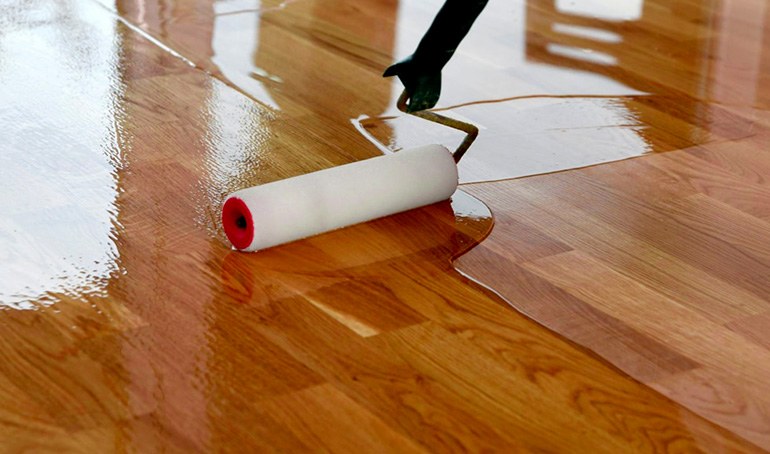 Close-up of a roller applying finish to a hardwood floor