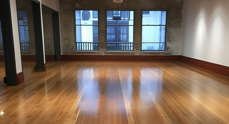 A large, empty room with a recently sanded floor.